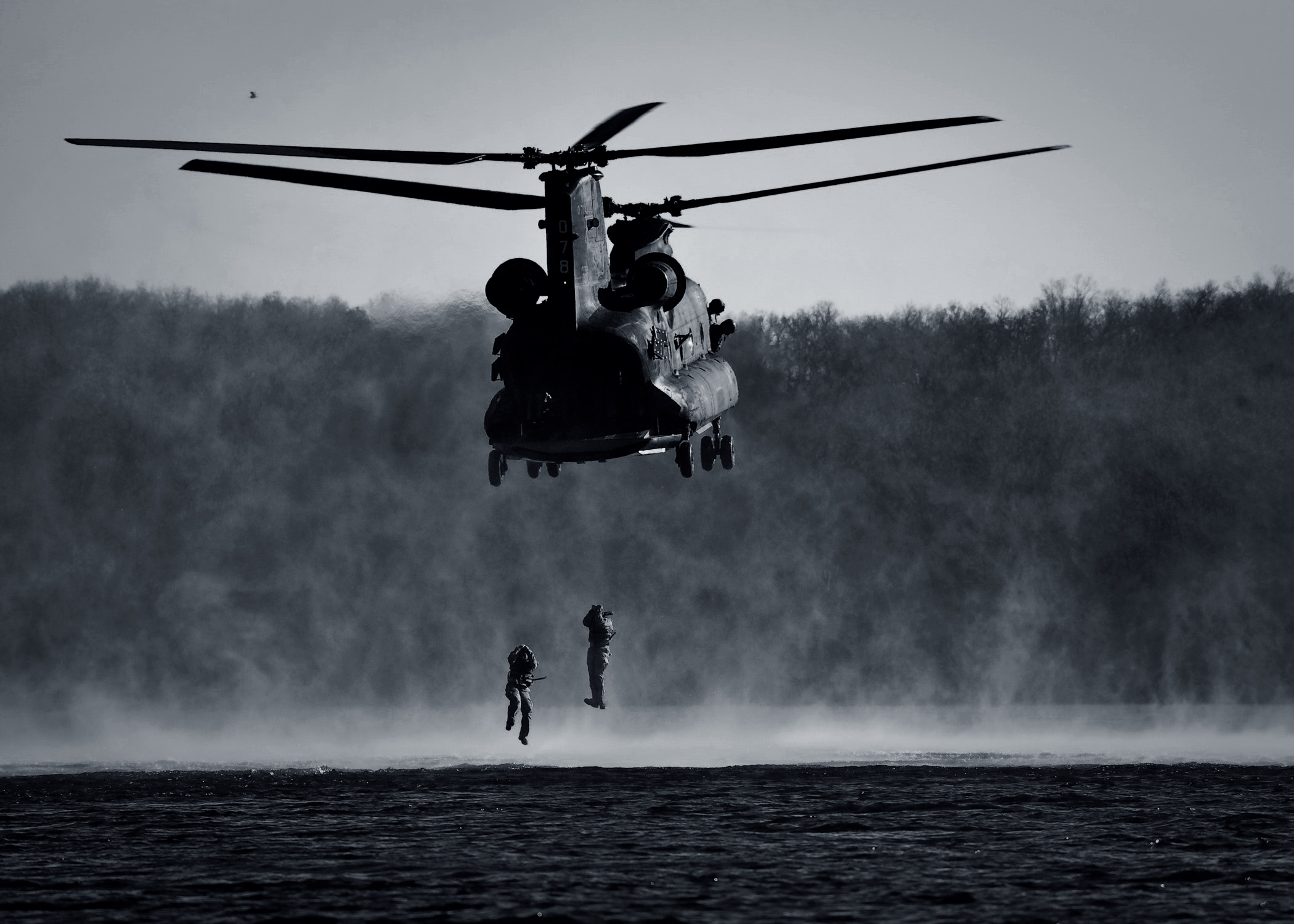 Militärhelikopter som vinschar ner soldater i havet